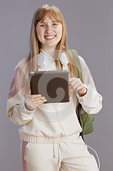 happy trendy girl in beige tracksuit with backpack