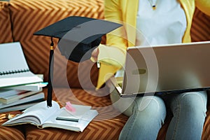 Happy trendy housewife with laptop showing graduation cap