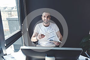 Happy trendy man is sitting at table