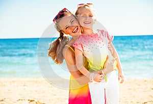 Happy trendy mother and child in colorful clothes on seacoast