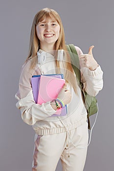 happy trendy teenage girl in beige tracksuit showing thumbs up
