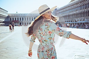 Happy trendy traveller woman in floral dress having excursion photo