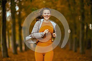 happy trendy woman in fitness clothes in park running