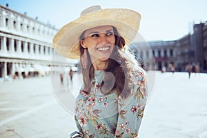 Happy trendy woman in floral dress with hat sightseeing