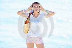 Happy trendy woman listening to music on seacoast