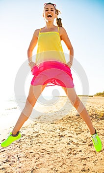 Happy trendy woman on seacoast in evening jumping