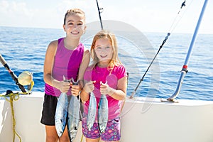 Happy tuna fisherwomen kid girls with fishes catch