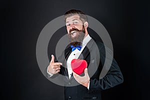 happy tuxedo man pointing finger on heart. happy valentines day. be my valentine.