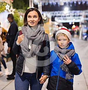 Happy tween boy and his mom walking at street Christmas fair