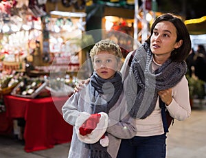 Happy tween boy and his mom walking at street Christmas fair