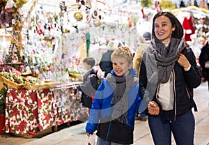 Happy tween boy and his mom walking at street Christmas fair