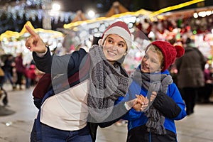 Happy tween boy and his mom walking at street Christmas fair