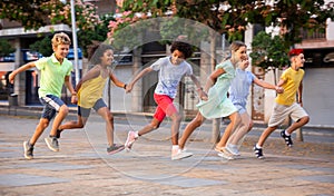 Happy tween friends running together on summer city street