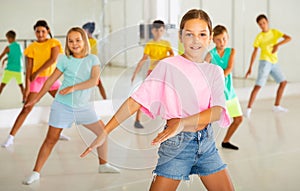 Happy tween girl dancing during group class in choreographic studio