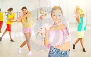 Happy tween girl dancing during group class in choreographic studio