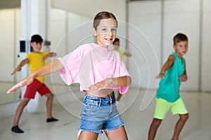 Happy tween girl dancing during group class in choreographic studio