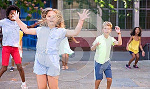 Happy tween girl jumping with friends on city street