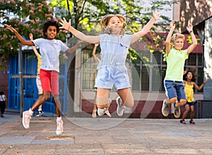 Happy tween girl jumping with friends on city street