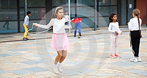 Happy tweenager girl skipping rope in schoolyard