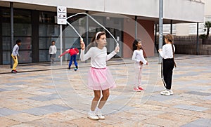 Happy tweenager girl skipping rope in schoolyard