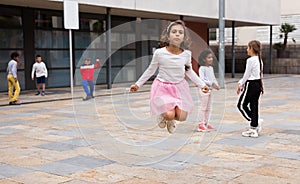 Happy tweenager girl skipping rope in schoolyard