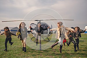 Happy tweenager girls running on airfield after flying in helicopter