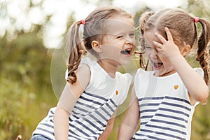 Happy twin sisters children. Girls sister in a park at a picnic laugh, smile