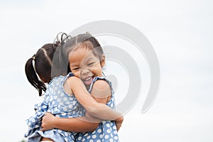 Happy two asian child girls hugging each other with love