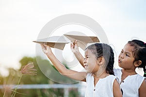 Happy two asian child girls playing with toy paper airplane