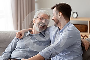 Happy two generations male family laugh talking bonding on sofa