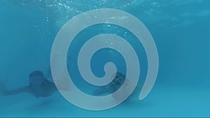 Happy Two Girls Dive In Swimming Pool look at the camera, Underwater Shoot