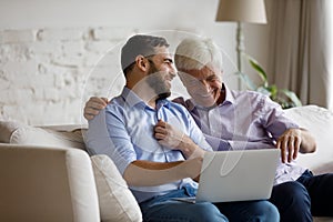 Happy two male generations family using laptop at home.