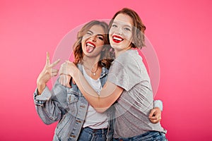 Happy two women friends hugging showing peace gesture