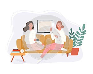 Happy two women sitting in the couch drinking coffee and talking at home. Smiling character spending time together