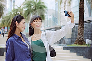 Happy two young women taking selfie on city street