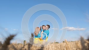 A happy Ukrainian family hugs a child in a wheat field. Meeting of parents with the child.