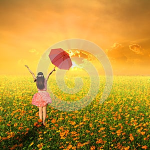 Happy umbrella woman jumping in flower garden and sunset
