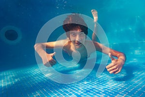 Happy underwater portrait of boy thumb up in pool