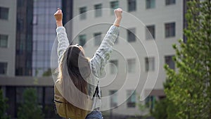 Happy university teenager girl female student with arms raised