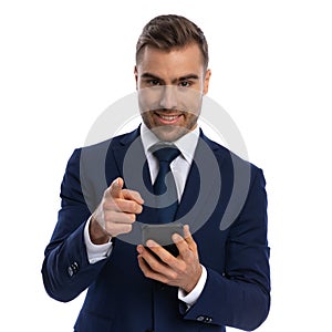 happy unshaved man holding phone and pointing finger