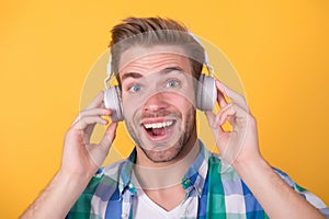 Happy unshaven man listen to music yellow background, headphones