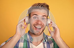 Happy unshaven man listen to music yellow background, headphones