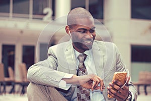 Happy urban professional man using smart phone listening to music