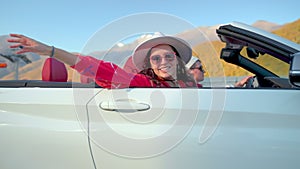 Happy vacation of couple traveling in convertible car in mountains valley.