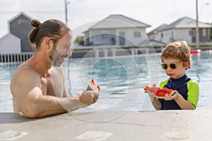 Happy vacation kid boy and father eat watermelon have fun enjoy at swimming pool. children and parent cheerful activity relaxing