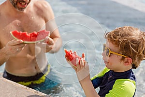 Happy vacation kid boy and father eat watermelon have fun enjoy at swimming pool. children and parent cheerful activity relaxing