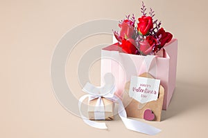 Happy valentine day card and envelope with gift box and rose in paper bag on beige background