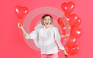 Happy Valentine Day. Curly blonde woman in angel wihgs with red heart shaped balloons. Female cupid.