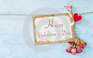 Happy Valentine`s card with little paper heart clip and paper flower on blue texture background