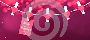 Happy Valentine`s Day background banner - White paper note hang on wooden clothes pegs with wooden hearts on a string isolated on